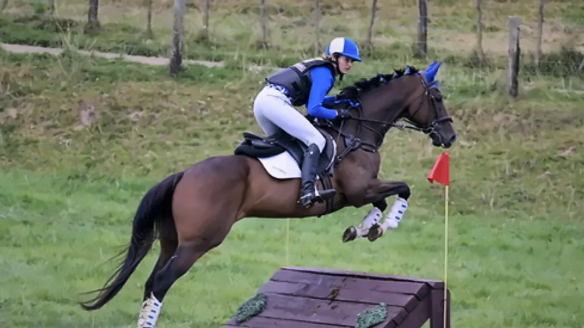 Jess jumping a cross-country fence in blue